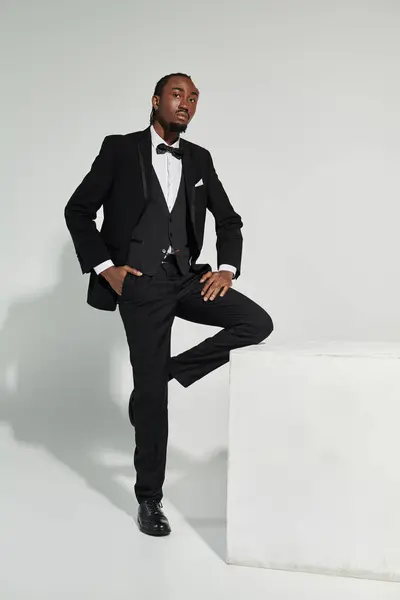 A sharply dressed young man stands poised in a suit, showcasing elegance and confidence in a minimalist setting. — Stock Photo