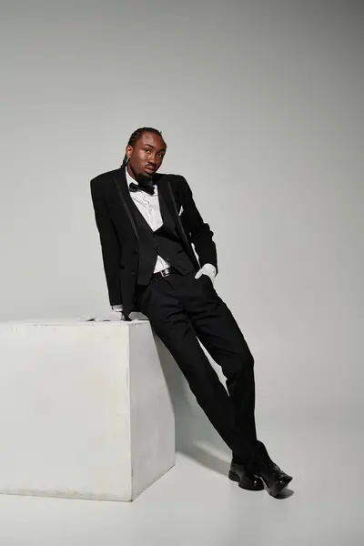 Dressed in a formal suit and vest, a young man exhibits elegance while posing against a grey background. — Stock Photo