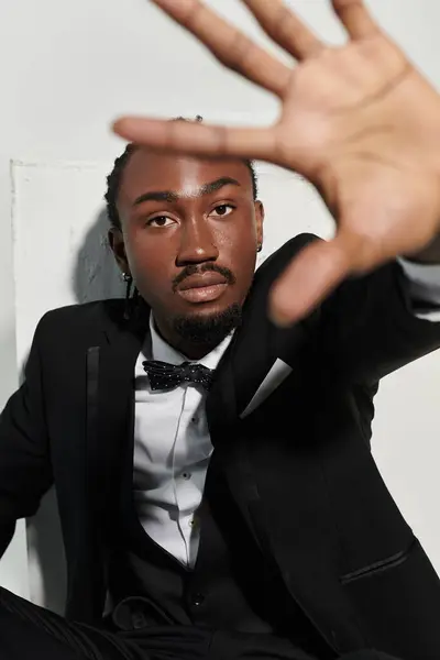 A young African American man in a suit and vest strikes a confident pose, showcasing elegance on grey. — Stock Photo