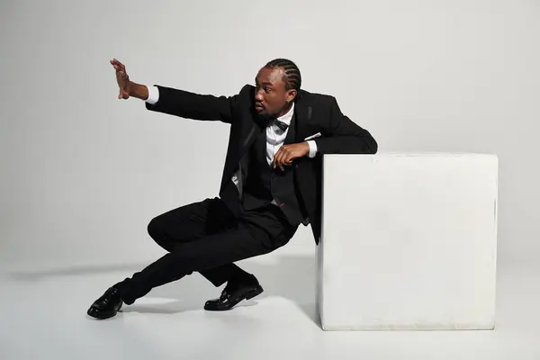 A young man in a tailored suit poses stylishly, showcasing confidence and elegance in a neutral setting. — Stock Photo