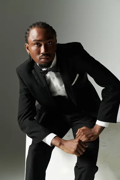 A young African American man in a sharp suit exudes confidence as he poses against a sleek grey backdrop. — Stock Photo