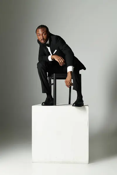 A young man dressed in a sharp suit poses confidently on a pedestal, exuding elegance and charisma. — Stock Photo