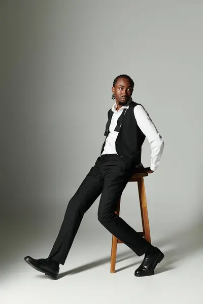 A young African American man in a tailored suit exudes confidence while posing on a stool. — Stock Photo