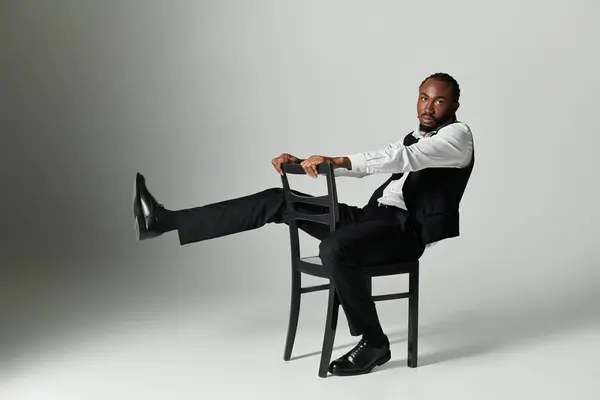 A young man dressed in a sophisticated suit showcases style and confidence while lounging on a chair. — Stock Photo