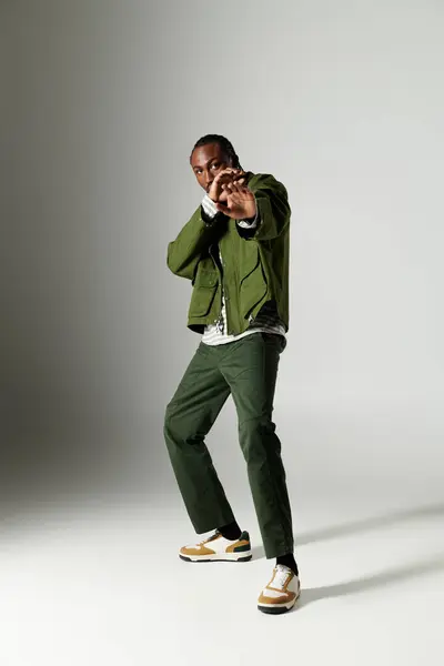 A young African American man strikes a confident pose in fashionable green attire, showcasing his style. — Stock Photo