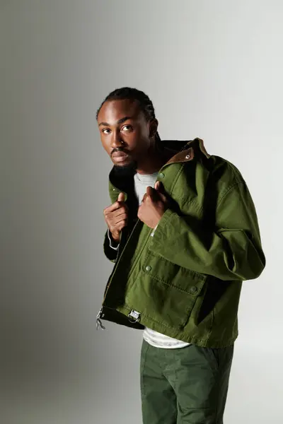 A young African American man exudes confidence in stylish green attire while posing against a neutral backdrop. — Stock Photo