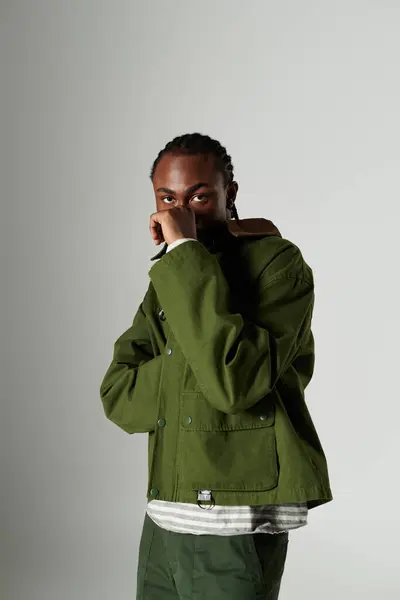 A young man dressed in trendy green clothing showcases his unique style while striking a pose. — Stock Photo