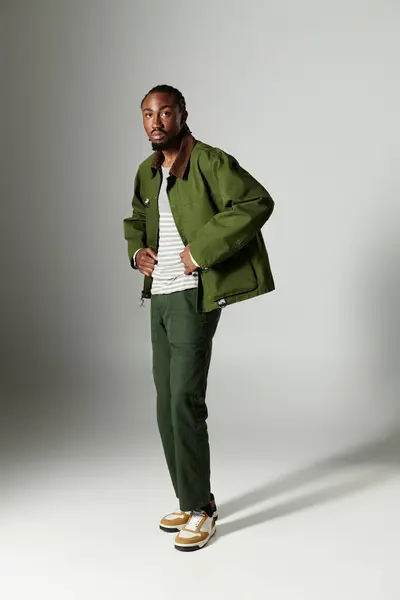 Un giovane uomo vestito in elegante abbigliamento verde mette in mostra il suo senso della moda in uno sfondo neutro. — Stock Photo