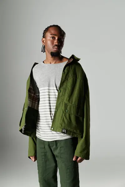 A young African American man showcases his trendy green outfit, exuding confidence and style. — Stock Photo