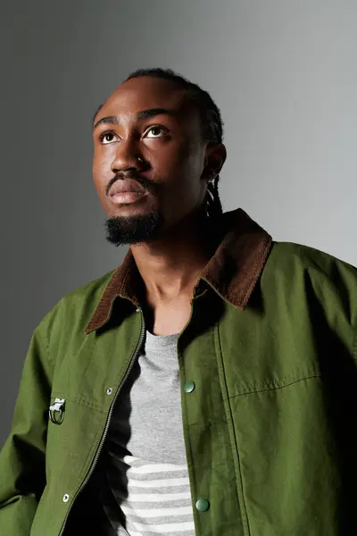 A young man showcases his unique style in an elegant green outfit while striking a thoughtful pose. — Stock Photo