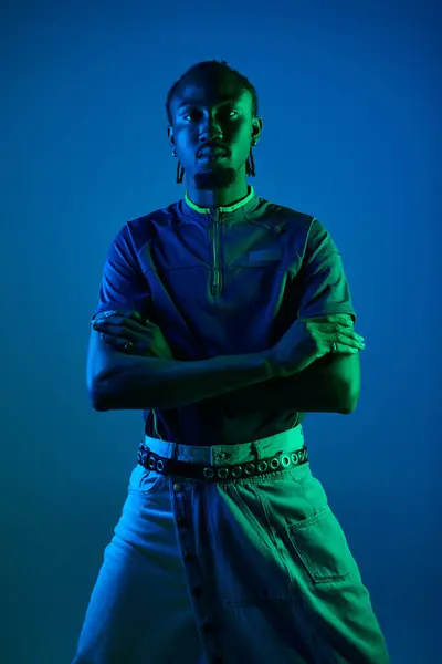 A young African American man showcases his style while posing confidently under neon lights. — Stock Photo