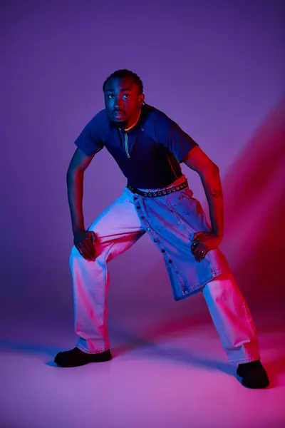 A young African American man showcases his unique style with a fierce pose under glowing neon lights. — Stock Photo