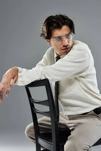 A young man in formal attire sits confidently on a chair, showcasing his stylish fashion sense and poise. — Stock Photo