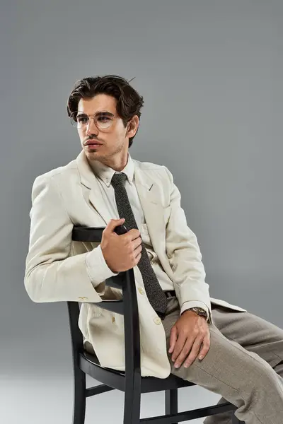 A young man dressed in elegant formal wear strikes a poised pose while seated on a chair. — Stock Photo