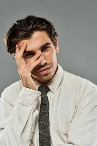 A young, handsome man poses thoughtfully in formal wear, showcasing elegance and style in a studio setting. — Stock Photo