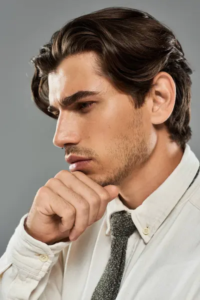A handsome young man dressed in sharp formal attire contemplates in a studio, showcasing elegance and poise. — Stock Photo