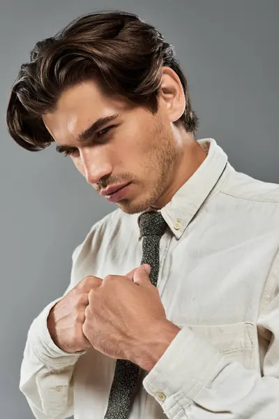 A well-dressed young man stands confidently, adjusting his tie, radiating charm and sophistication. — Stock Photo