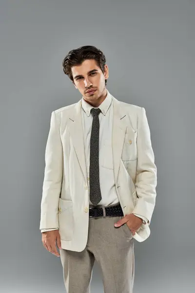 Dressed in elegant formal wear, a young man strikes a pose with confidence in a modern studio setting. — Stock Photo