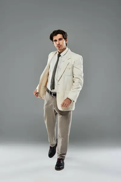 A young handsome man showcases his charm in sleek formal attire, exuding confidence in a studio setting. — Stock Photo