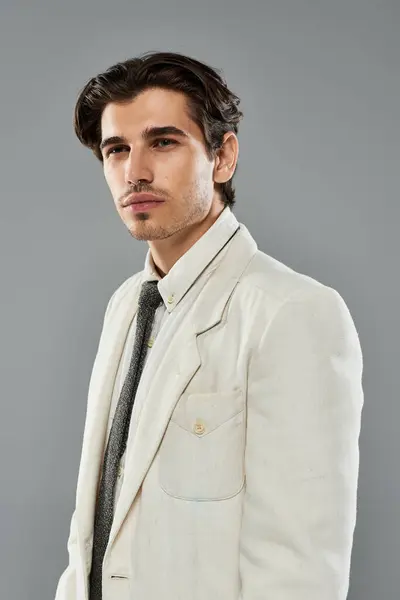 A young, handsome man showcases elegant formal wear while striking a confident pose in a modern studio. — Stock Photo