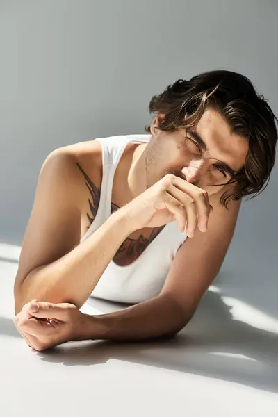 A young man with tattoos displays confidence while resting his arm on a surface in casual attire. — Stock Photo