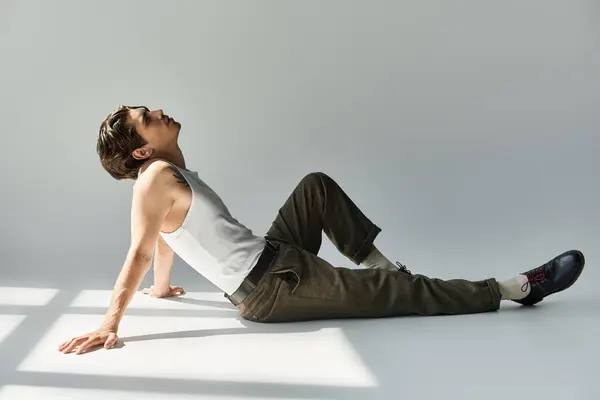 A young man with a tattoo relaxes in a tank top, exuding confidence while embodying a stylish vibe. — Stock Photo
