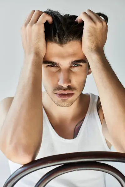 A young, handsome man in a tank top shows deep emotions with a thoughtful look against a grey background. — Stock Photo