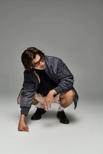 A young man confidently poses in an autumn outfit, highlighting his stylish flair and unique expression. — Stock Photo