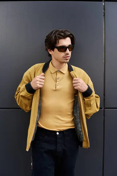 Ein junger Mann posiert selbstbewusst in einem trendigen Herbst-Outfit, das Stil und Komfort vor einer schicken Kulisse vereint. — Stockfoto