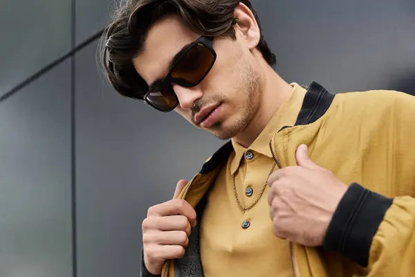 A confident young man showcases his trendy autumn outfit while posing against a modern cityscape. — Stock Photo