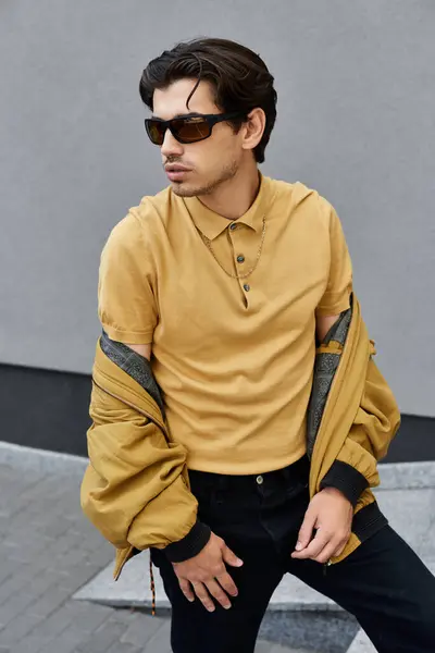 A trendy young man showcases his autumn style with confidence while posing against a modern backdrop. — Stock Photo
