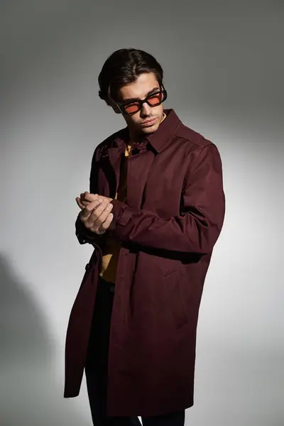 A young, handsome man poses gracefully in a chic autumn outfit, radiating modern style with confidence. — Stock Photo