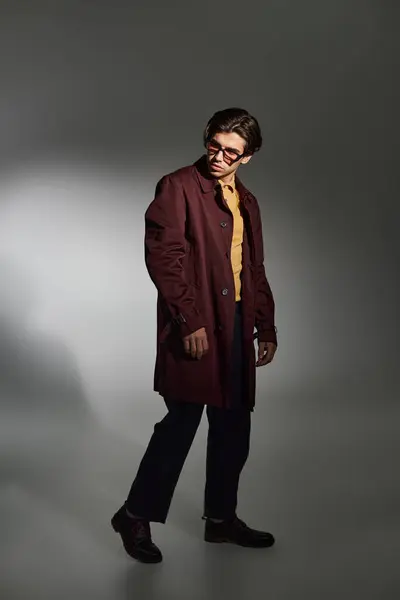 A young man stands confidently in a trendy autumn outfit, showcasing his unique fashion flair in a studio. — Stock Photo