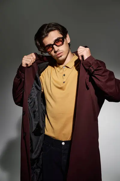 A stylish young man showcases his trendy autumn outfit while striking a confident pose against a neutral backdrop. — Stock Photo
