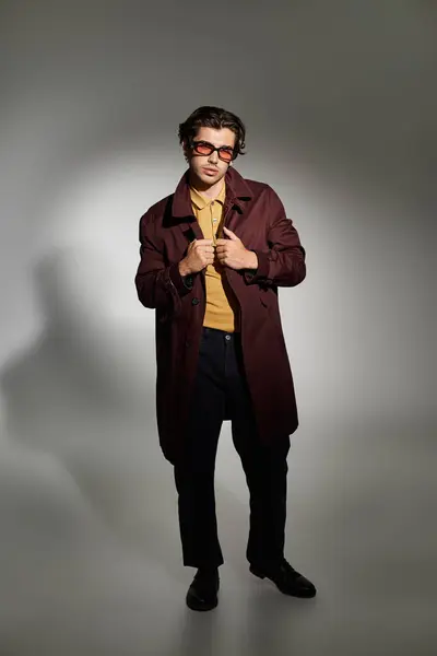 A young, handsome man poses confidently in a trendy autumn outfit, highlighting his unique style and charm. — Stock Photo