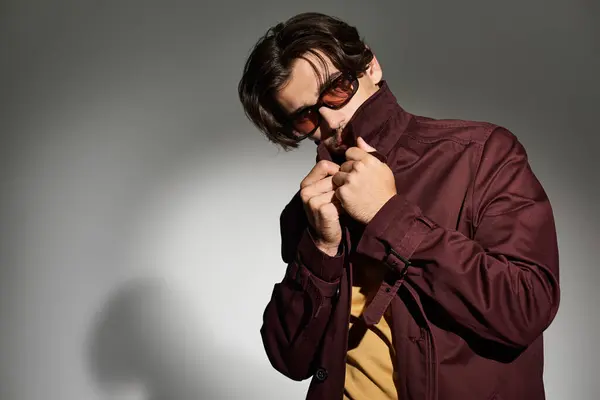 Dressed in a stylish autumn ensemble, a young man poses confidently as he adjusts his look. — Stock Photo