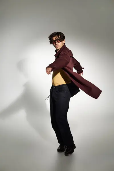 A stylish young man poses confidently in a chic autumn outfit against a neutral backdrop. — Stock Photo