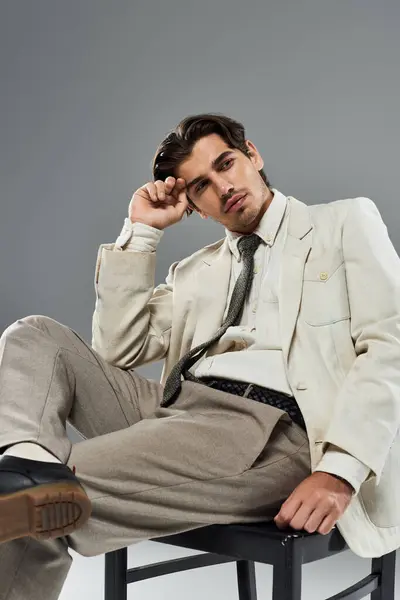 A dapper young man sits casually, contemplating life while showcasing his elegant formal attire in a studio. — Stock Photo