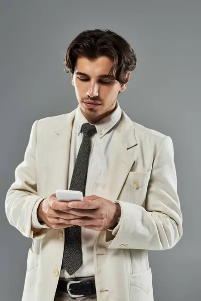 A young, handsome man dressed in elegant attire engages with his smartphone, exuding confidence and elegance. — Stock Photo