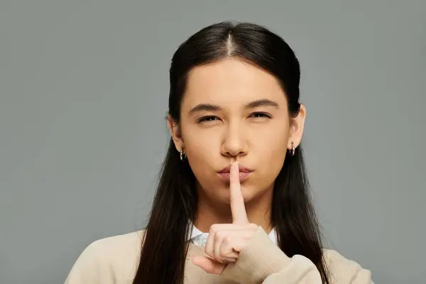 A young, emotional woman in a fashionable outfit gestures for silence, radiating confidence. — Stock Photo