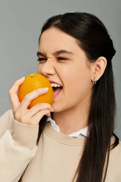 A young woman joyfully interacts with an orange, showcasing her vibrant emotions and style. — Stock Photo