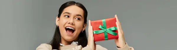 A young woman expresses excitement while showcasing a vibrant gift with a big smile. — Stock Photo