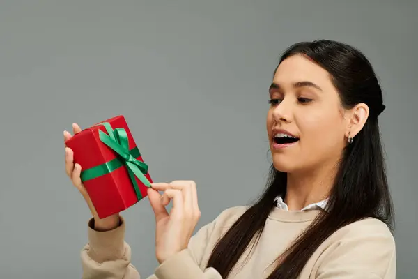 A joyful woman in chic attire unwraps a beautifully tied gift. — Stock Photo