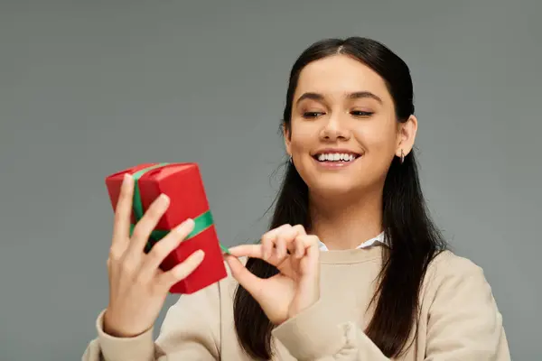 A stylish young woman unwraps a vibrant gift, joyfully expressing her delight. — Stock Photo