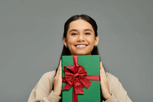 Her bright smile radiates joy as she proudly holds a beautifully wrapped green gift. — Stock Photo