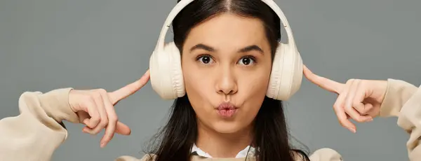 A young woman in fashionable attire listens to music with headphones, conveying deep emotions. — Stock Photo