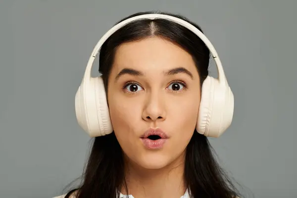A young woman with long hair shows an emotional reaction while listening to music. — Stock Photo