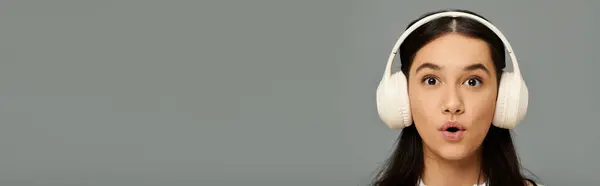 A young woman showcases her surprise in fashionable attire while enjoying music through headphones. — Stock Photo