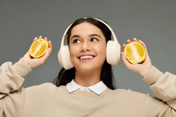 A happy young woman listens to music while playfully holding lemon halves, exuding joy. — Stock Photo