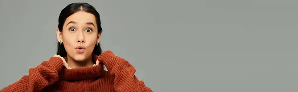 Una joven con un elegante suéter naranja transmite sorpresa con su expresiva reacción facial. — Stock Photo
